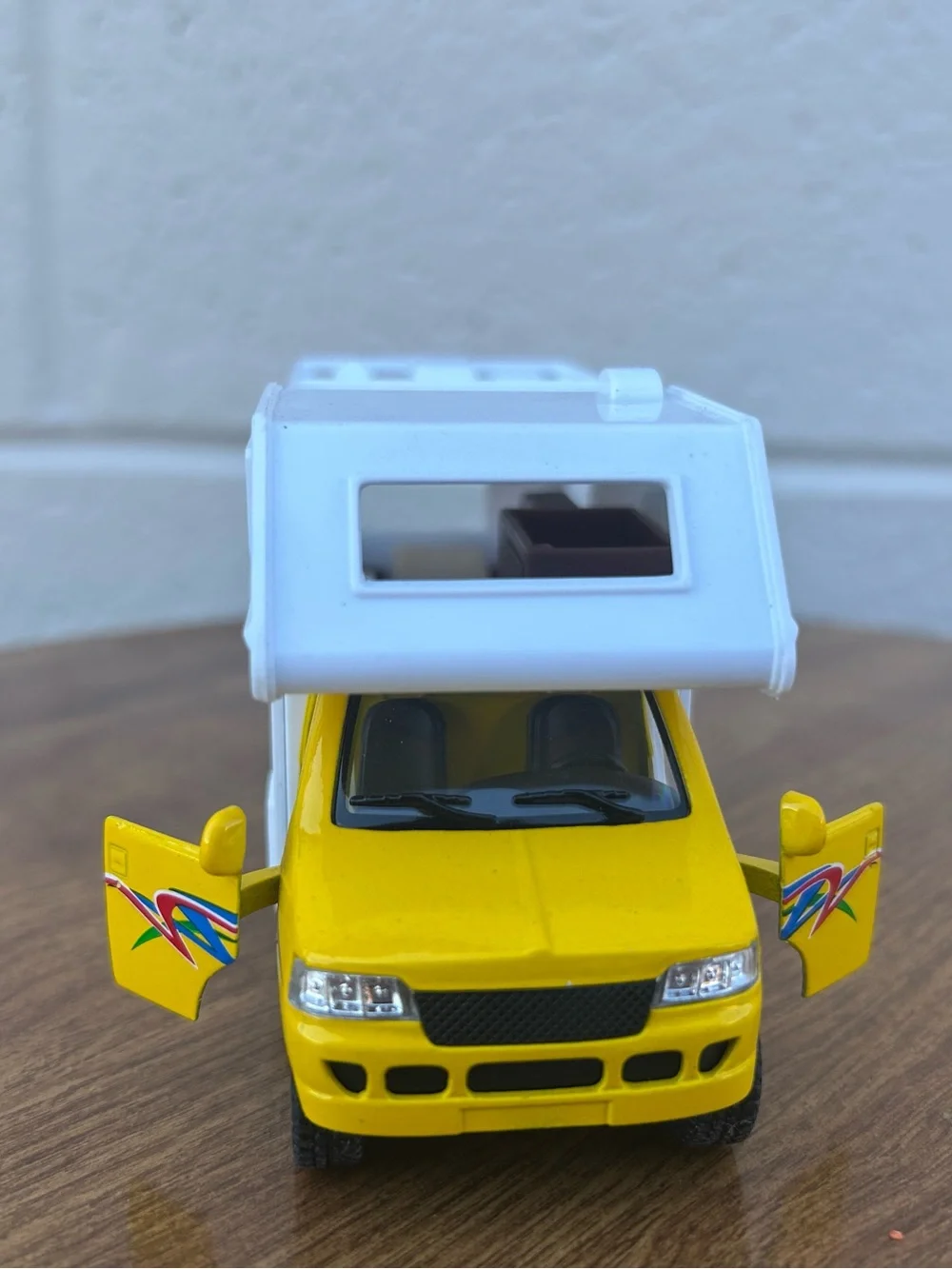 Bright yellow and white toy camper van with colorful beach graphics collectible